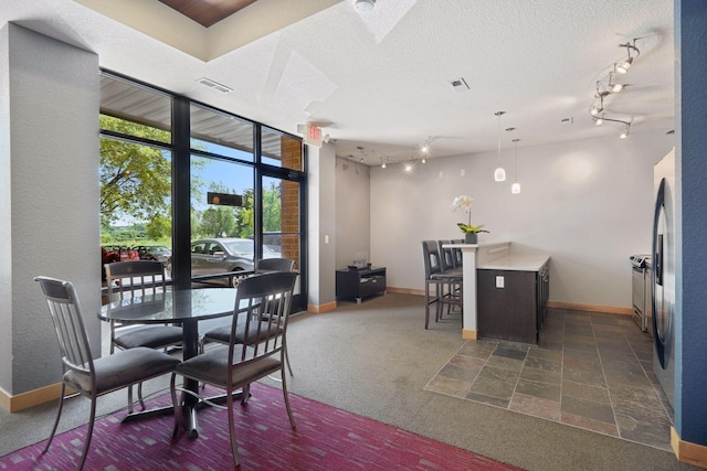 dining room with dark carpet, track lighting, and a textured ceiling