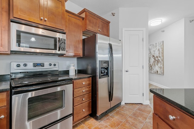 kitchen with light tile patterned floors, dark stone counters, and appliances with stainless steel finishes