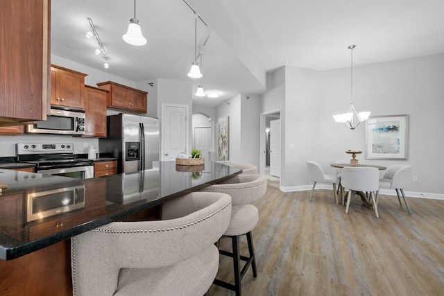 kitchen featuring pendant lighting, light hardwood / wood-style floors, a breakfast bar, and appliances with stainless steel finishes