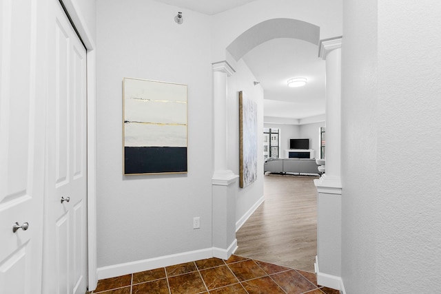 corridor featuring ornate columns and dark tile patterned floors