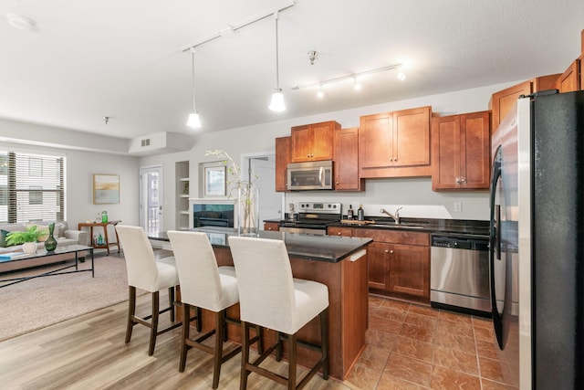 kitchen with pendant lighting, sink, a breakfast bar area, a center island, and stainless steel appliances