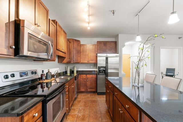 kitchen with pendant lighting, track lighting, appliances with stainless steel finishes, and sink