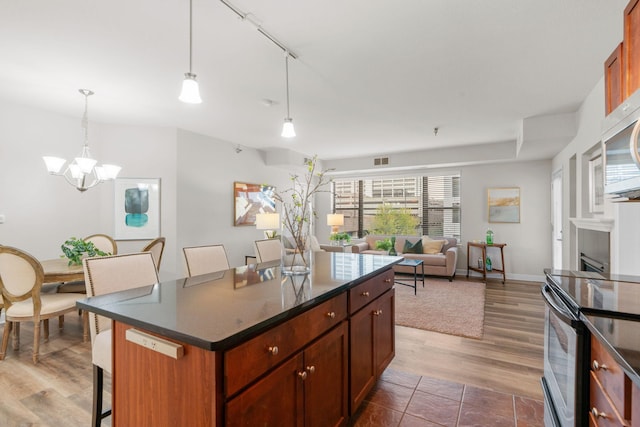 kitchen featuring electric stove, dark wood-type flooring, a kitchen island, decorative light fixtures, and a chandelier