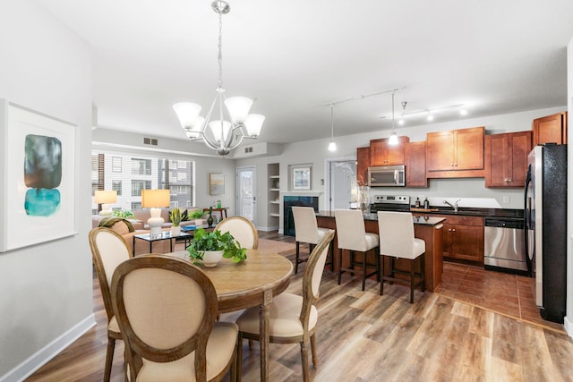 dining area with an inviting chandelier, sink, and light hardwood / wood-style flooring