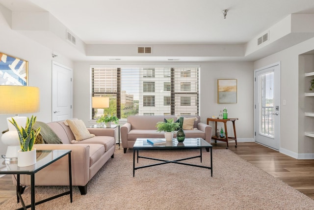 living room with built in shelves and wood-type flooring