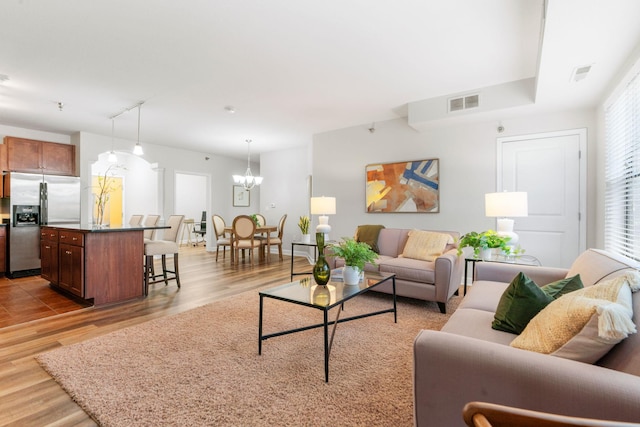 living room with rail lighting, a chandelier, and light hardwood / wood-style flooring