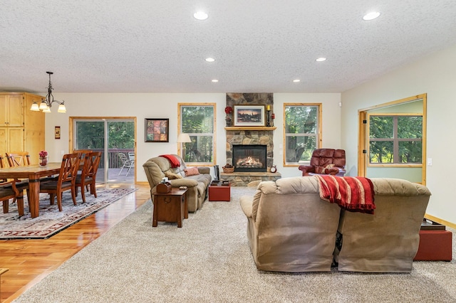 living room with a fireplace, a notable chandelier, light hardwood / wood-style flooring, and a textured ceiling