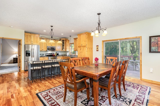 dining room featuring a notable chandelier, light hardwood / wood-style flooring, and a textured ceiling