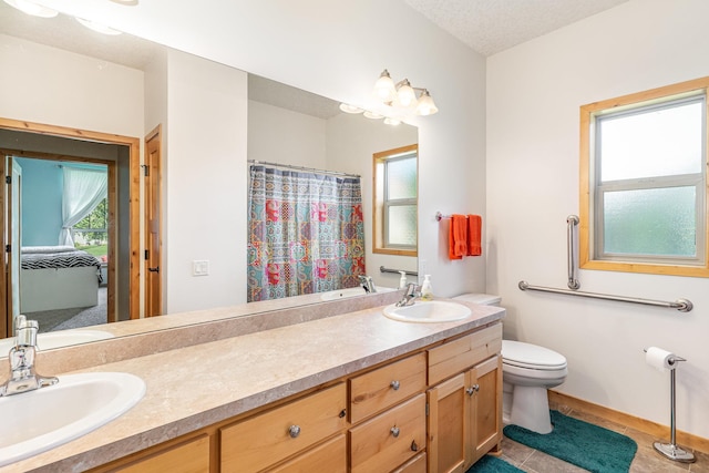 bathroom featuring vanity, a textured ceiling, plenty of natural light, and toilet