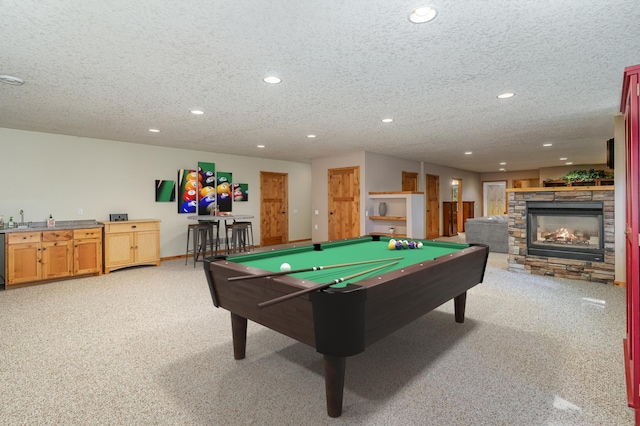 recreation room featuring a stone fireplace, light carpet, a textured ceiling, and billiards