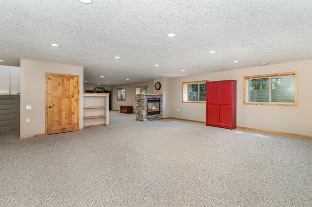 basement with a stone fireplace, a textured ceiling, and carpet