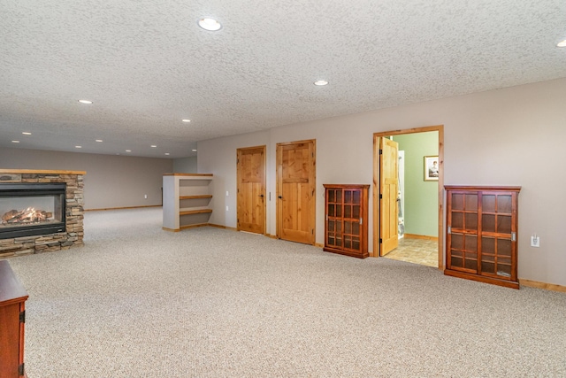 carpeted living room with a stone fireplace and a textured ceiling