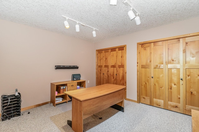 carpeted office space featuring rail lighting and a textured ceiling