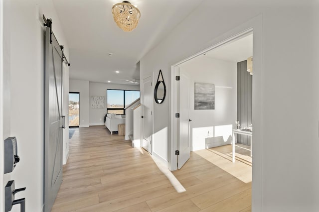 hall with a barn door and light hardwood / wood-style flooring