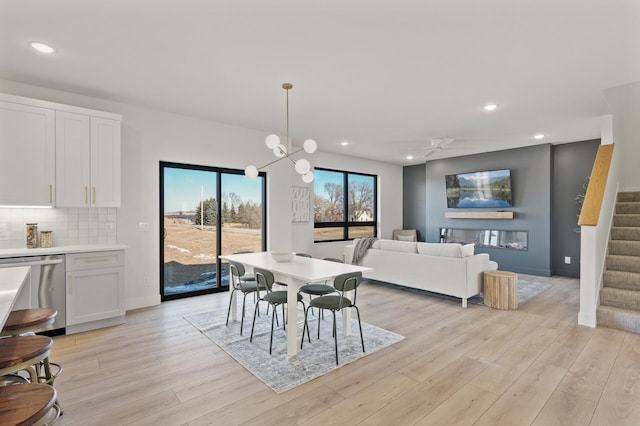 dining area featuring ceiling fan with notable chandelier and light wood-type flooring