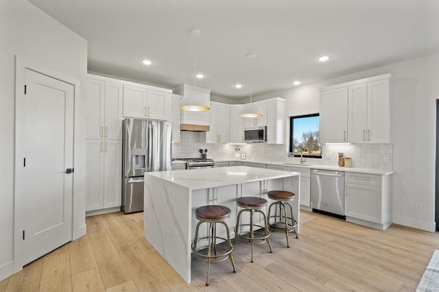 kitchen featuring a kitchen island, white cabinetry, stainless steel appliances, and a breakfast bar area