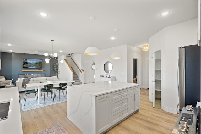 kitchen featuring a center island, light hardwood / wood-style floors, white cabinetry, hanging light fixtures, and stainless steel refrigerator