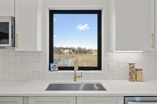 kitchen featuring tasteful backsplash, white cabinetry, sink, and appliances with stainless steel finishes