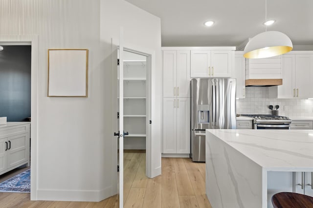 kitchen featuring white cabinets, appliances with stainless steel finishes, and pendant lighting