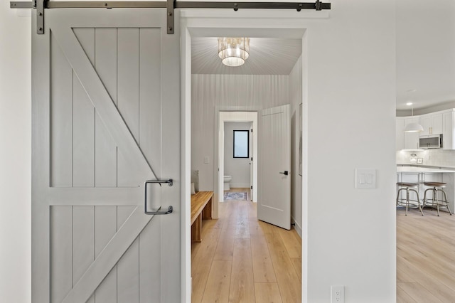 corridor featuring a barn door and light hardwood / wood-style floors