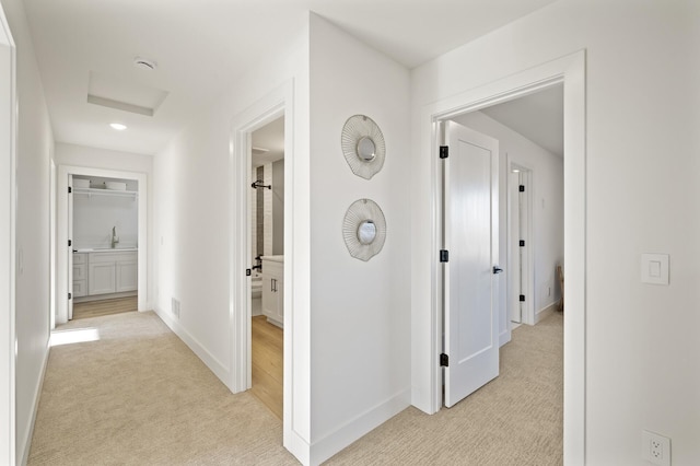 corridor featuring light colored carpet and sink