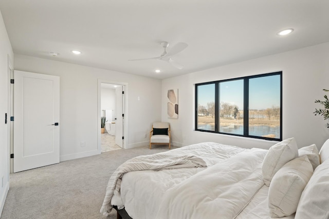 carpeted bedroom with ensuite bathroom and ceiling fan