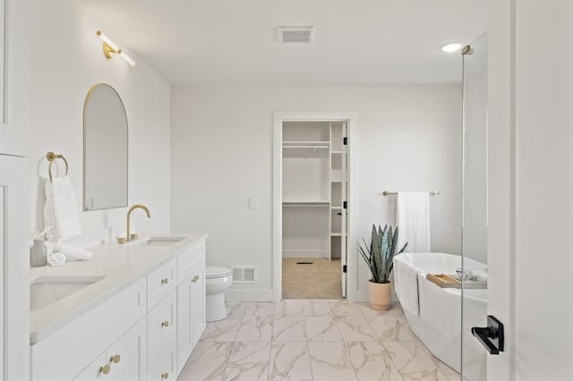 bathroom with a tub to relax in, vanity, and toilet