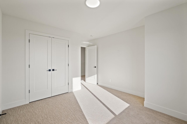 unfurnished bedroom with light colored carpet and a closet