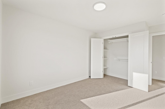 unfurnished bedroom featuring light colored carpet and a closet