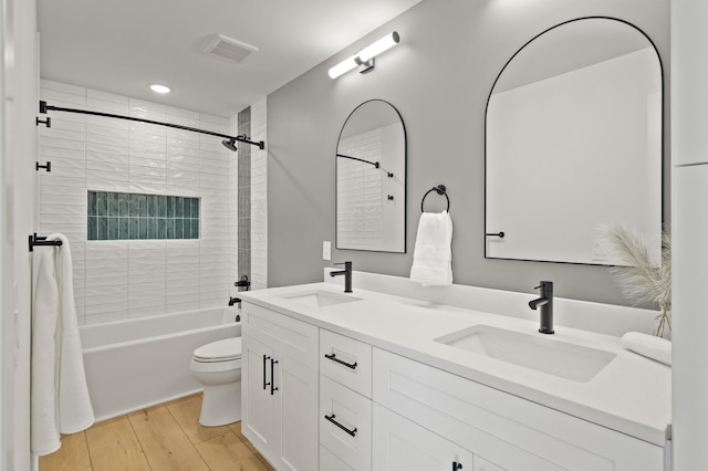 full bathroom with vanity, hardwood / wood-style flooring, toilet, and tiled shower / bath