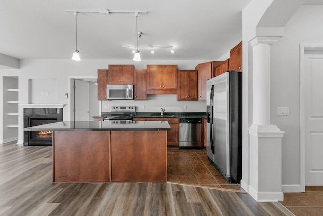 kitchen featuring sink, ornate columns, decorative light fixtures, a center island, and appliances with stainless steel finishes