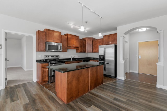 kitchen with sink, appliances with stainless steel finishes, hanging light fixtures, dark hardwood / wood-style floors, and a kitchen island