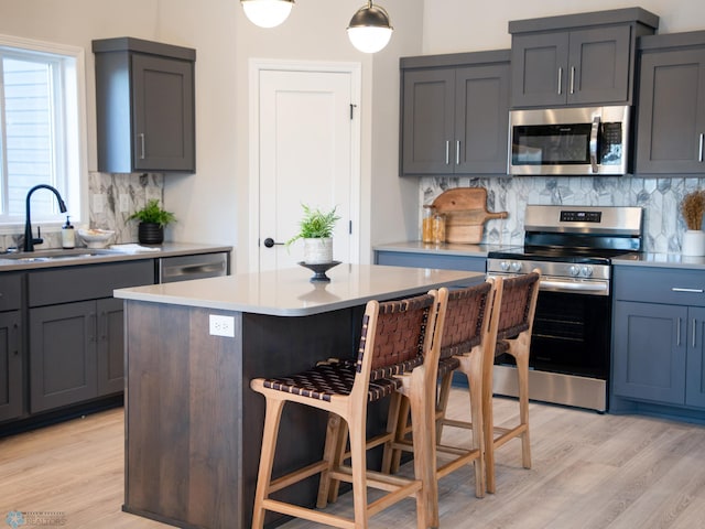 kitchen with backsplash, sink, a kitchen island, a kitchen bar, and stainless steel appliances