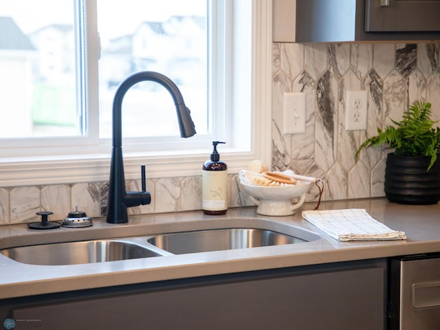 room details with gray cabinetry, decorative backsplash, and sink