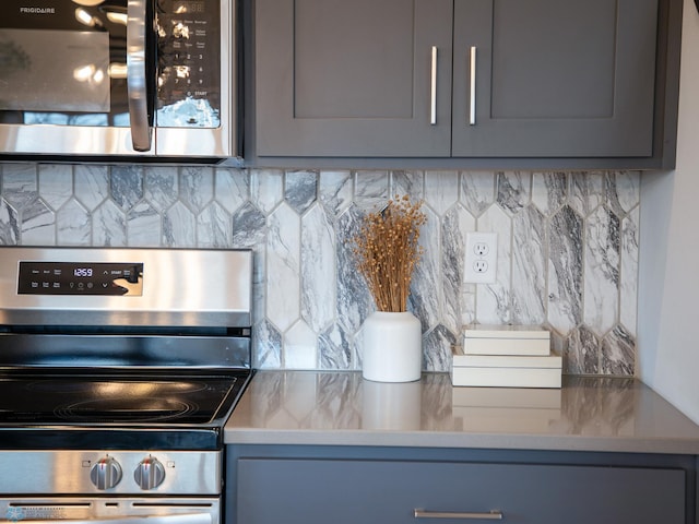 kitchen featuring gray cabinetry, appliances with stainless steel finishes, and tasteful backsplash