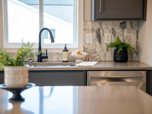 kitchen featuring stainless steel dishwasher, a healthy amount of sunlight, gray cabinetry, and sink