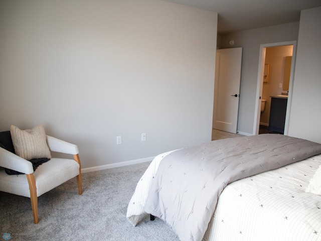 bedroom with ensuite bathroom and light carpet