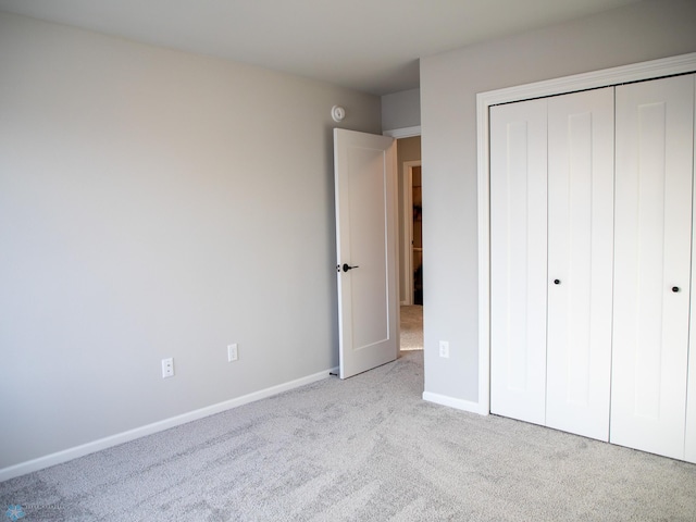 unfurnished bedroom with a closet and light colored carpet