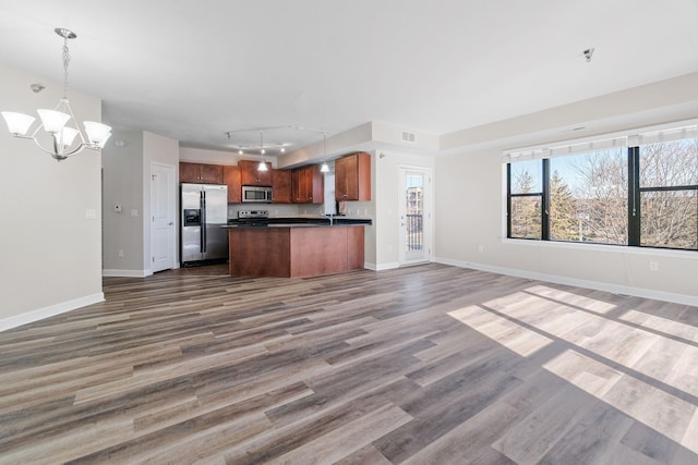 kitchen featuring stainless steel appliances, dark wood-type flooring, an inviting chandelier, and decorative light fixtures