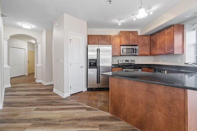 kitchen with ornate columns, appliances with stainless steel finishes, sink, and dark wood-type flooring