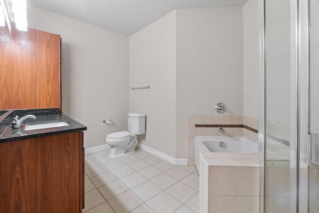 bathroom featuring tile patterned flooring, vanity, a relaxing tiled tub, and toilet