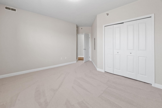 unfurnished bedroom featuring a closet and light carpet