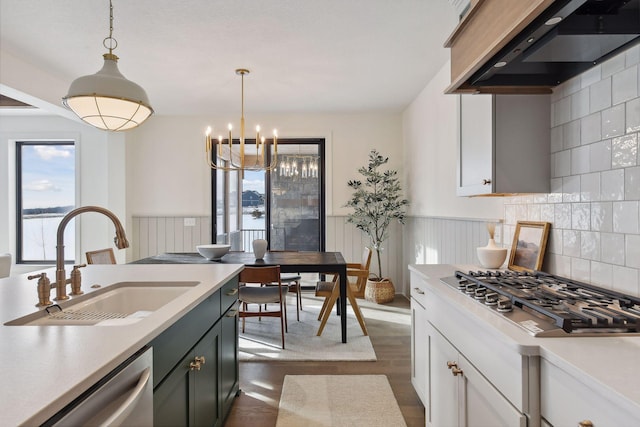 kitchen with sink, dark hardwood / wood-style floors, range hood, pendant lighting, and appliances with stainless steel finishes