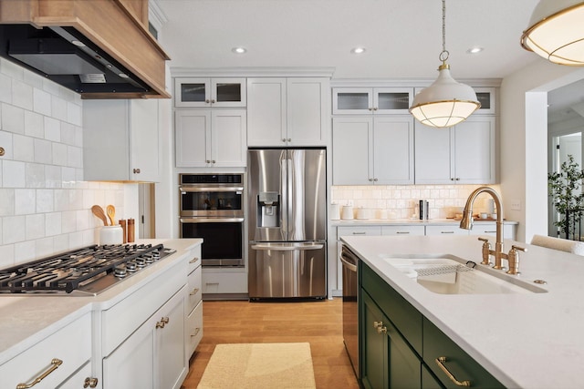 kitchen with sink, stainless steel appliances, decorative light fixtures, white cabinets, and custom range hood