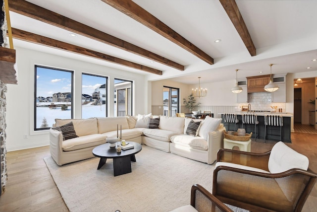 living room with a chandelier, beam ceiling, light hardwood / wood-style floors, and a water view