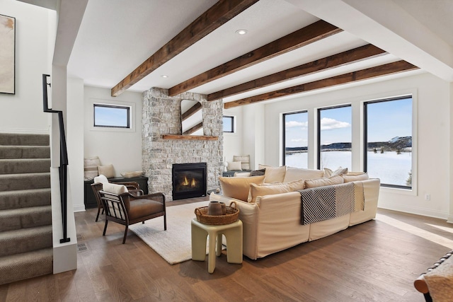 living room featuring beam ceiling, a fireplace, a water view, and dark hardwood / wood-style floors