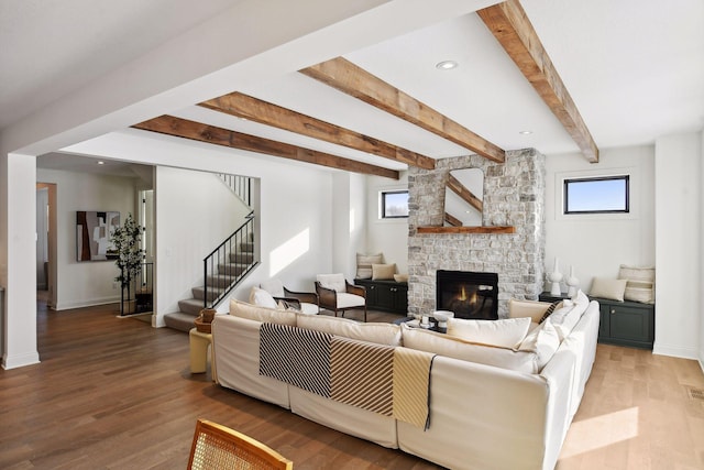 living room with a fireplace, beamed ceiling, and wood-type flooring