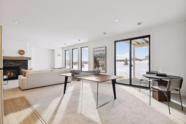 recreation room with a water view, light carpet, and a brick fireplace