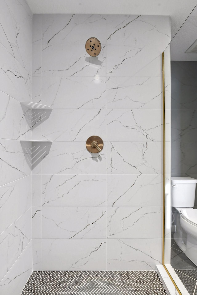 bathroom with toilet and a tile shower