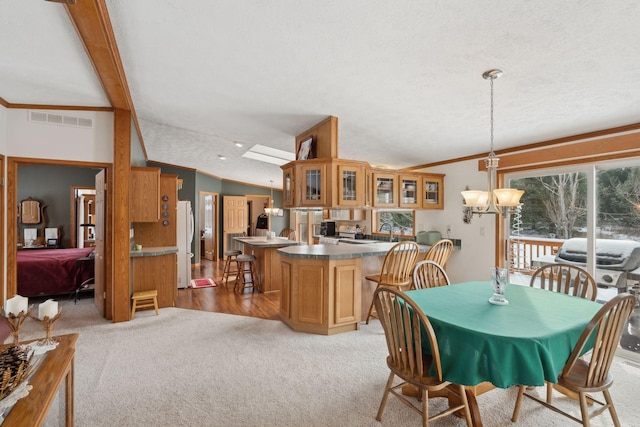 carpeted dining area featuring lofted ceiling with beams, ornamental molding, a textured ceiling, and an inviting chandelier